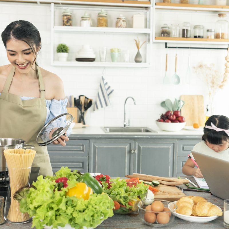 asian-young-single-mother-making-food-while-taking-care-child-kitchen